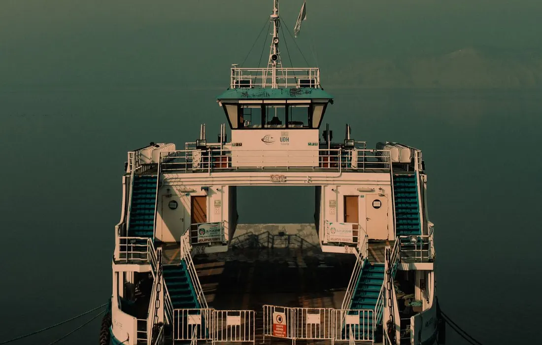 A peaceful ferry awaits departure in a tranquil, foggy harbor during dawn.