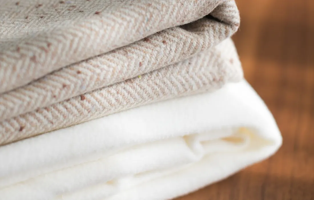 Folded soft blankets resting on a wooden floor.