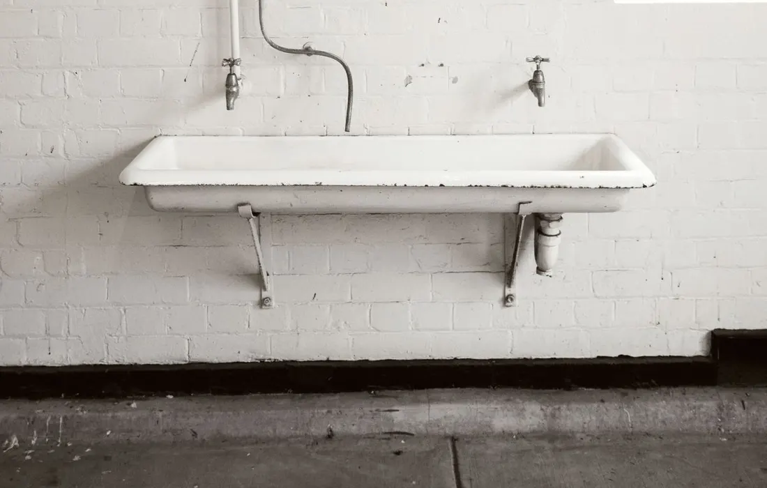 Exposed plumbing beneath a bathroom sink.
