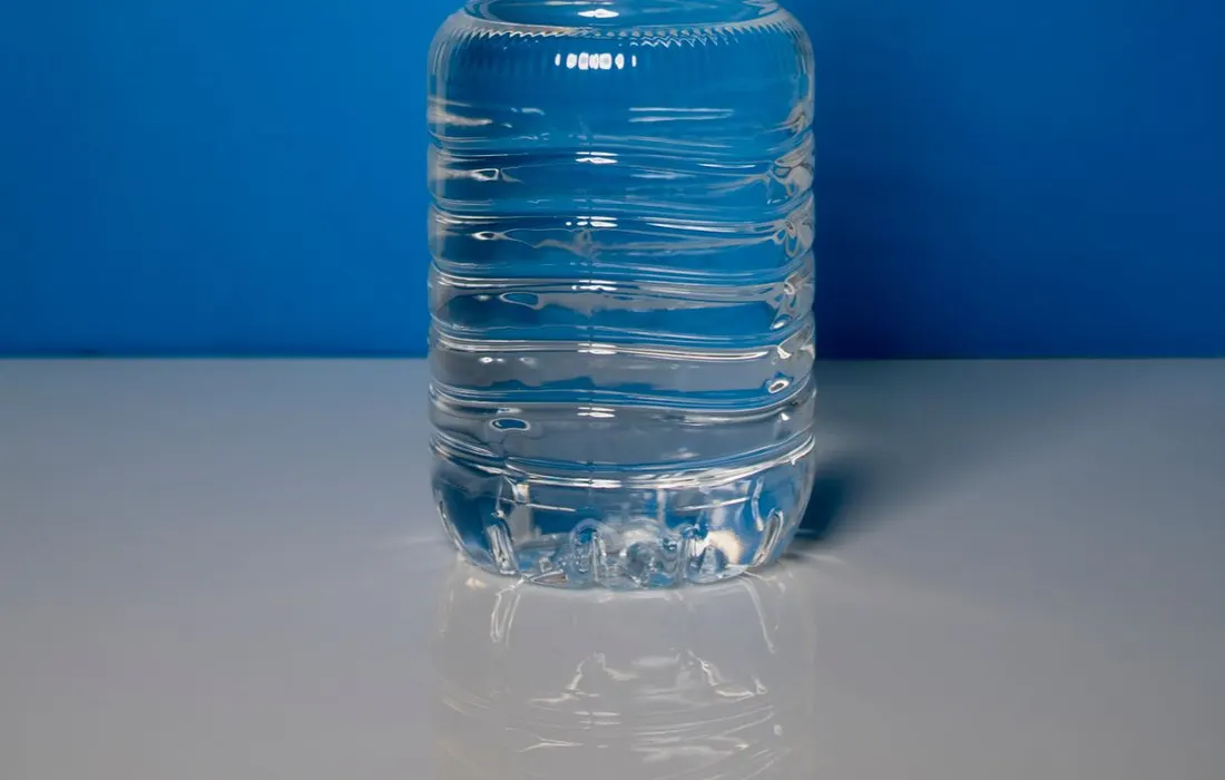 A clear bottle of water against a blue background.