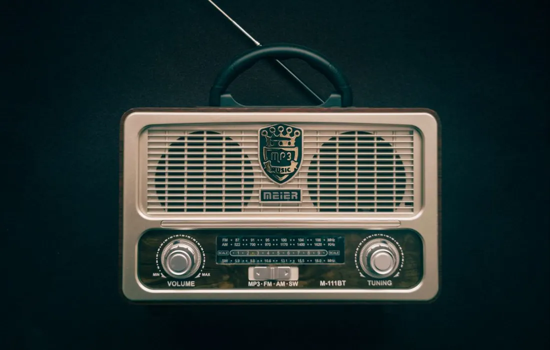 A portable radio with an extended aerial on a dark background.