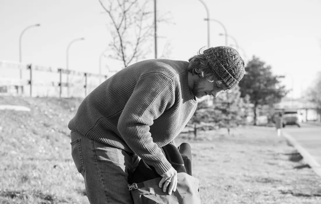 A person packing a backpack beside a road.