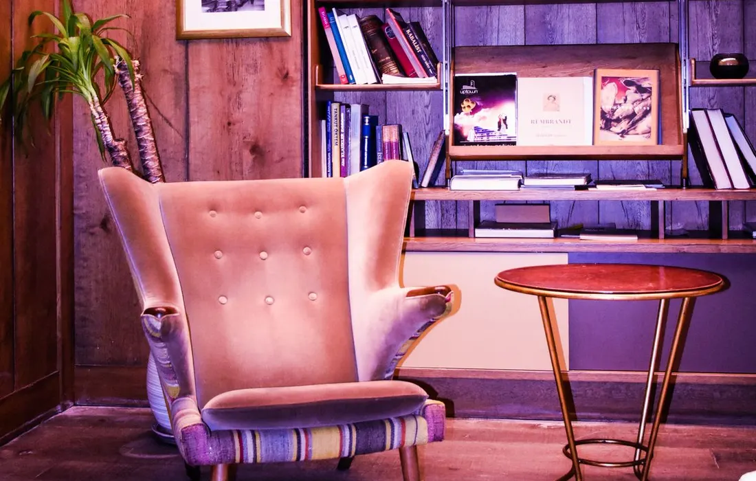 An armchair beside a bookshelf in a reading corner.