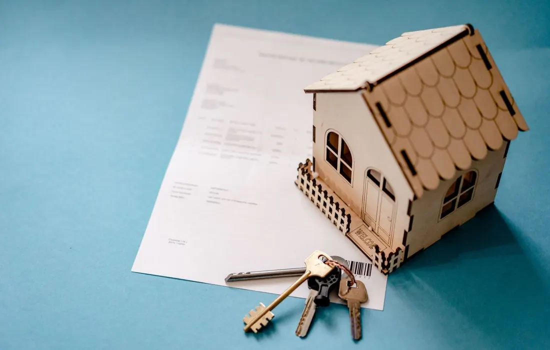 House keys, a document and a small wooden house model.