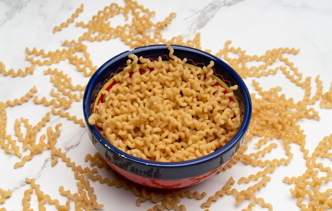 Uncooked spiral pasta in a colourful ceramic bowl.