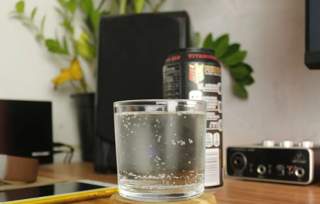 A glass of water, a phone and plants on a desk.