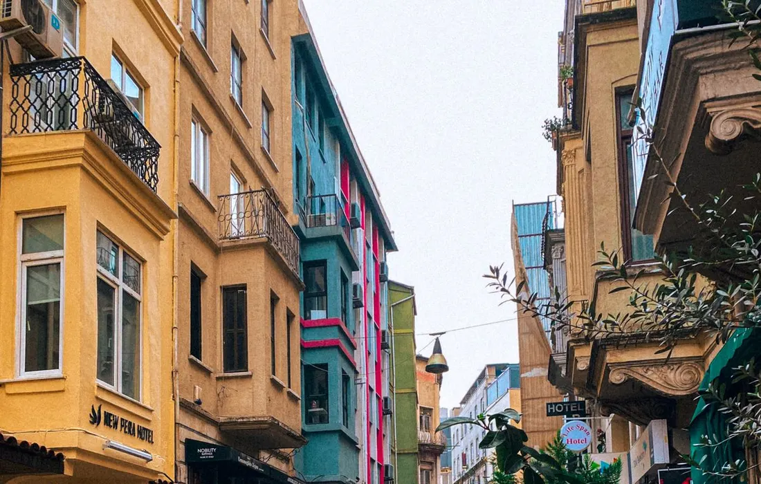 Explore a vibrant rainy street scene in Istanbul filled with colorful buildings and wet cobblestone road.