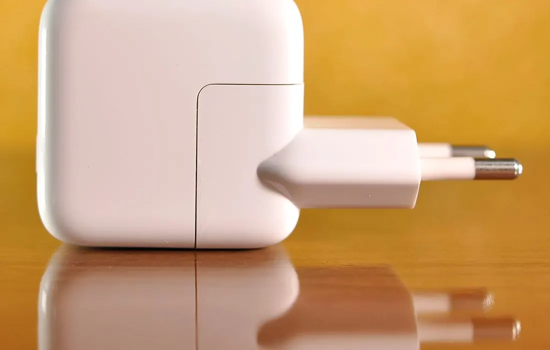 A white electrical power adaptor on a plain surface.