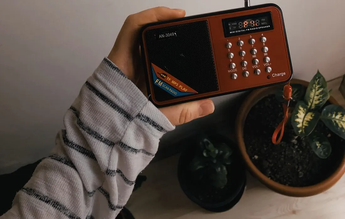 A hand holding a small portable radio.