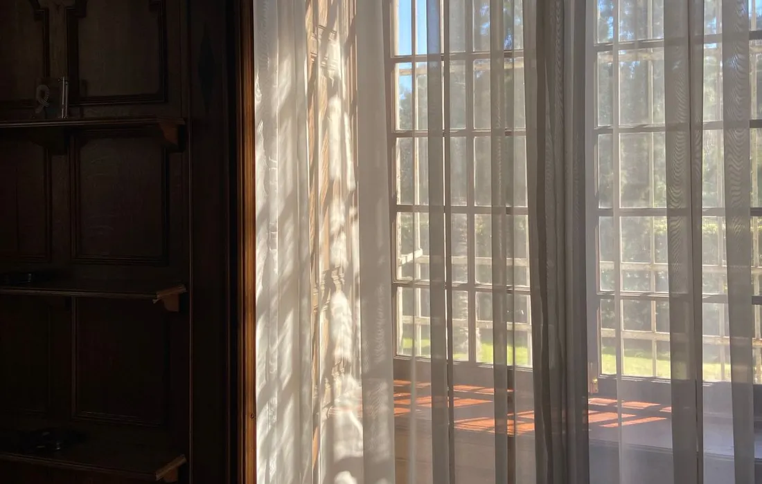 Sunlight passing through a curtained wooden window.