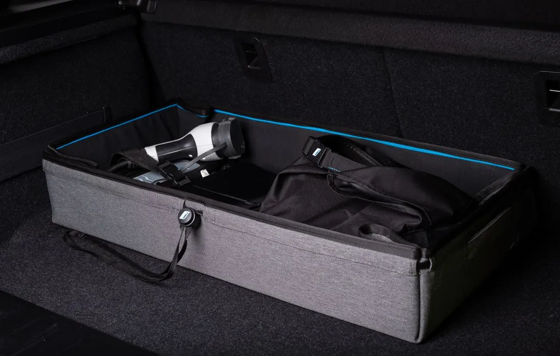 A storage bag and other travel items arranged inside a car boot.