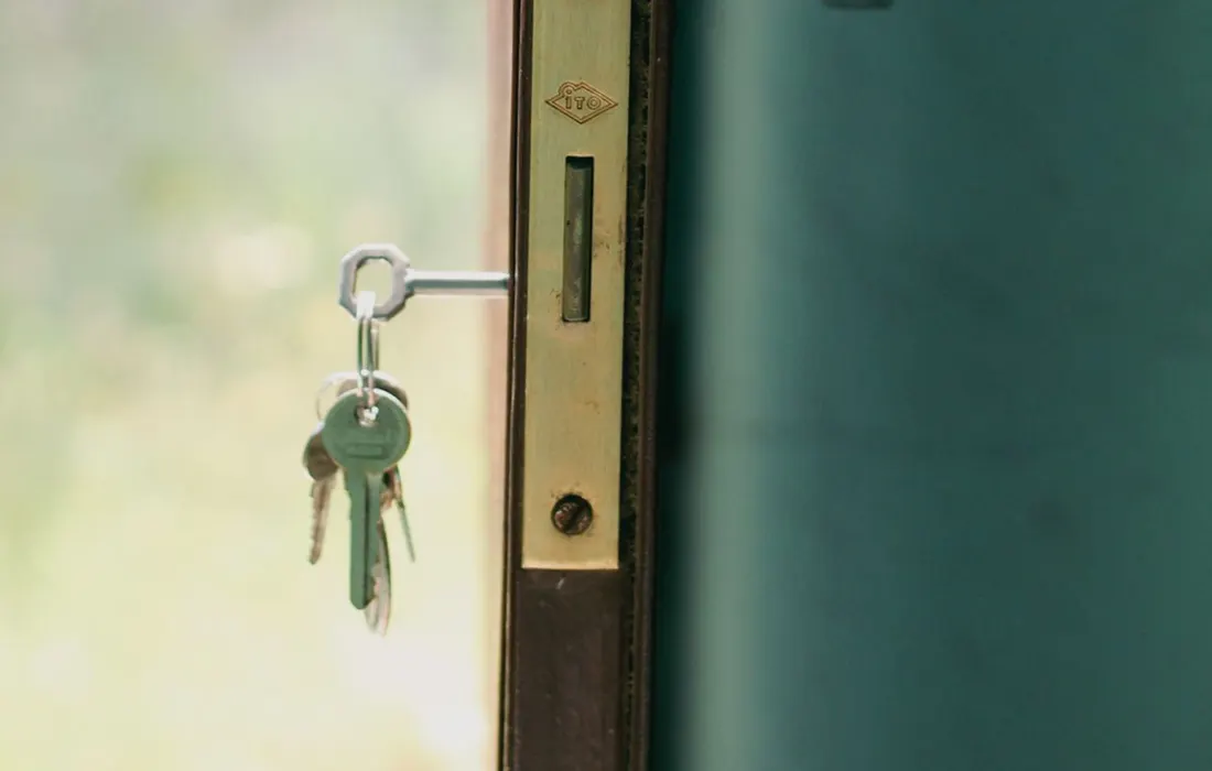 Keys inserted in the lock of an open door.