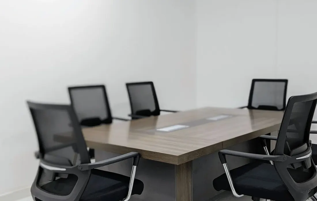 A conference table and black chairs in an empty office meeting room.