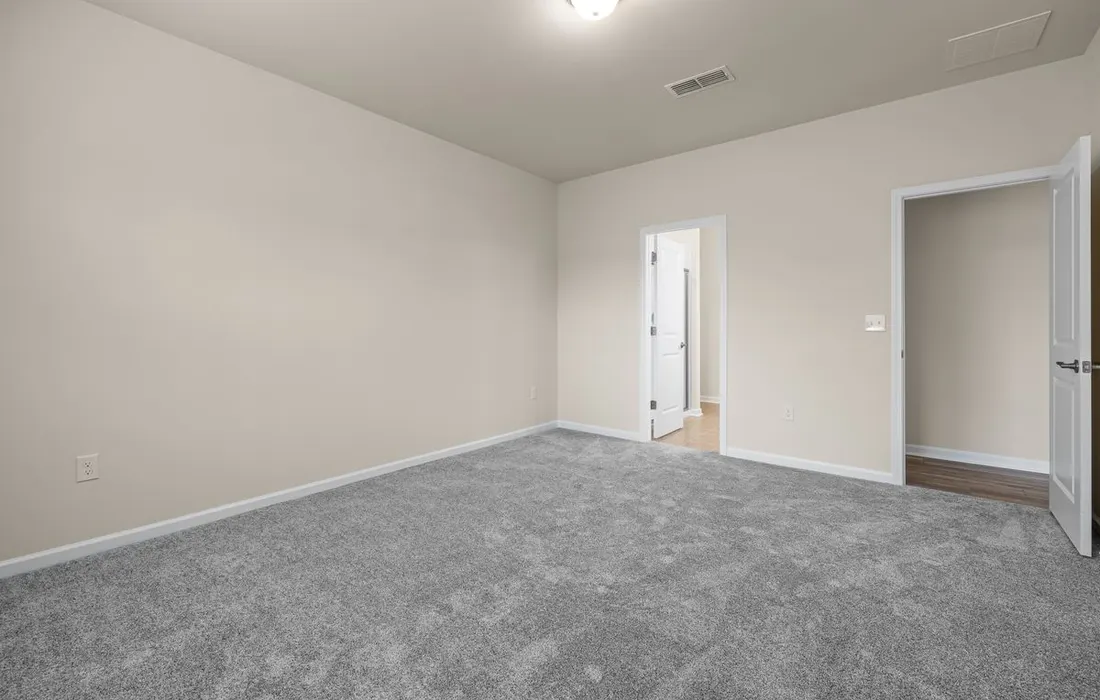 An unfurnished room with carpet and open interior doors.