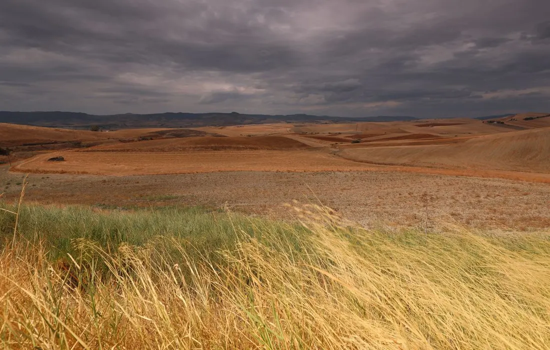 A broad rural landscape beneath storm clouds.