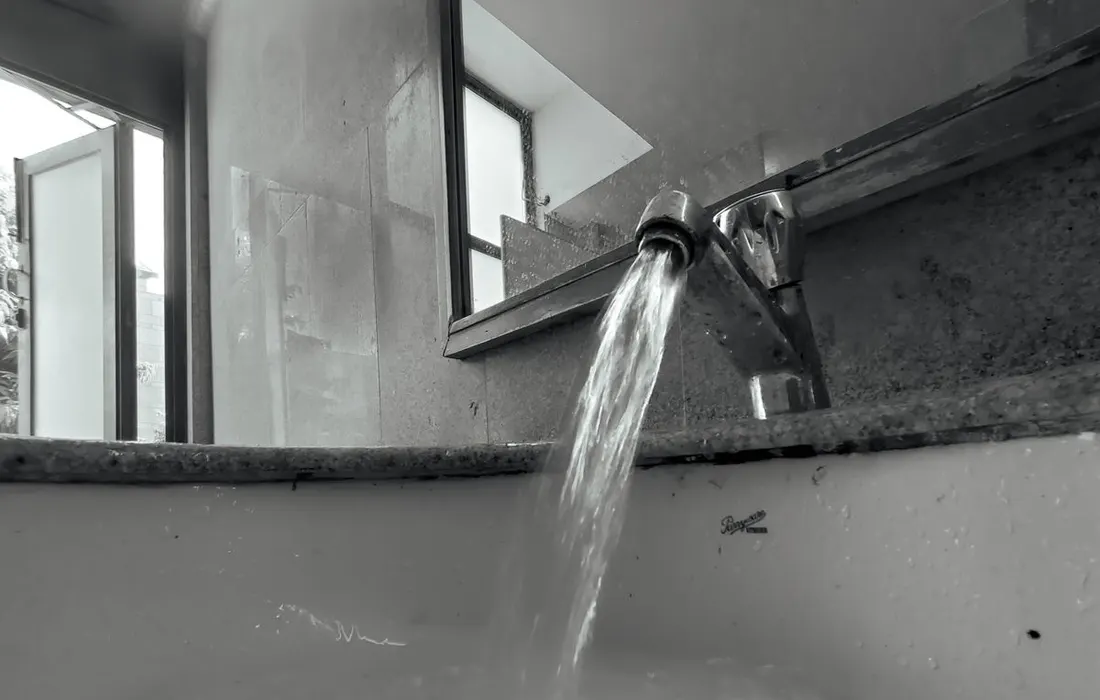 A black-and-white close-up of water running from a tap.