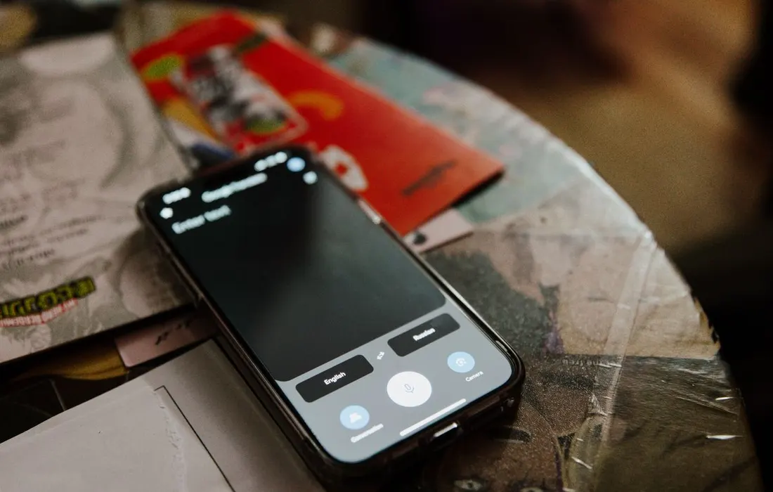 A smartphone lying beside books and handwritten notes on a table.