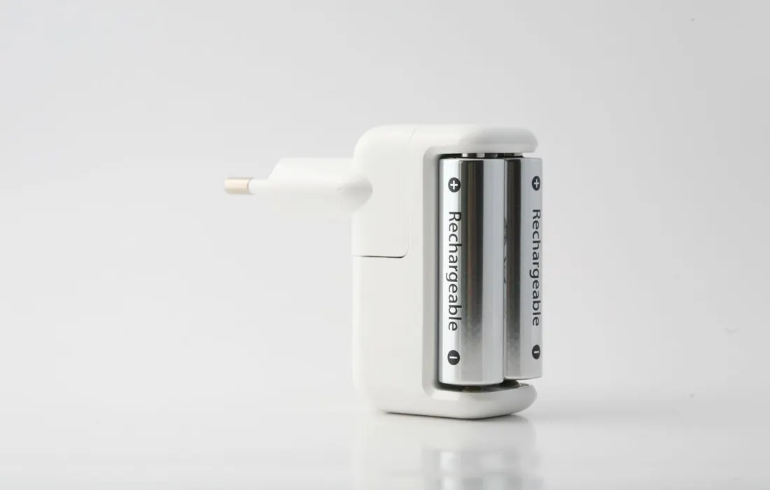An illustrative battery charger with two cylindrical cells on a white background.