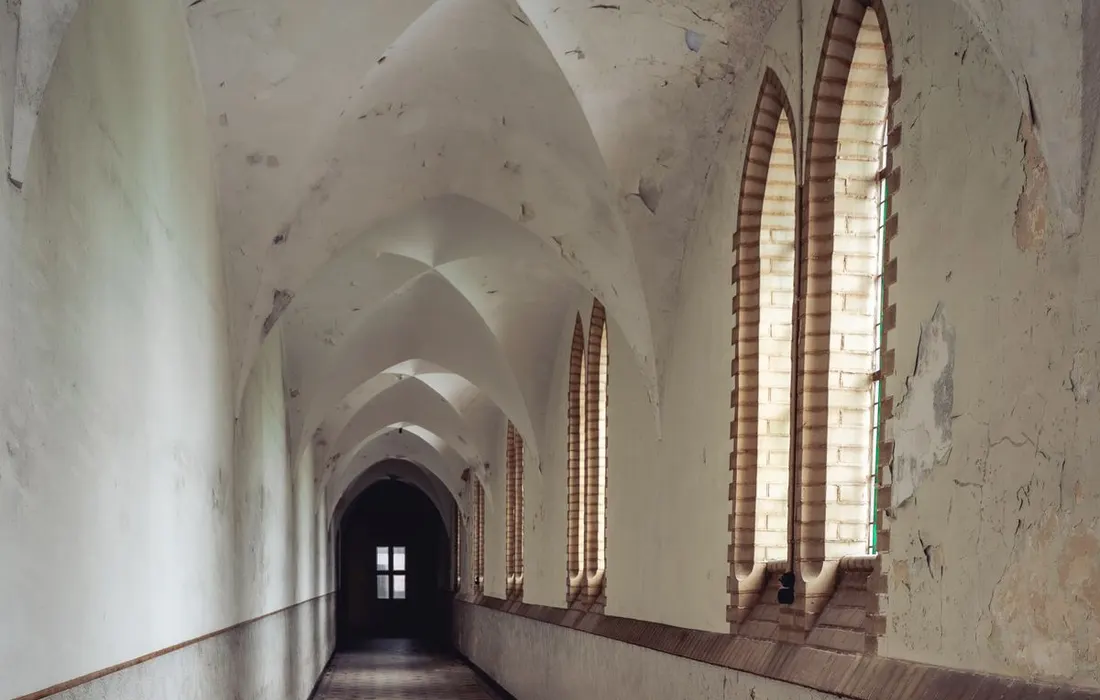 An empty wheelchair in an arched indoor corridor.