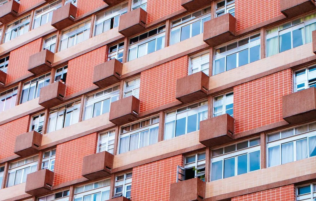 The windows and balconies of a red-brick apartment building.