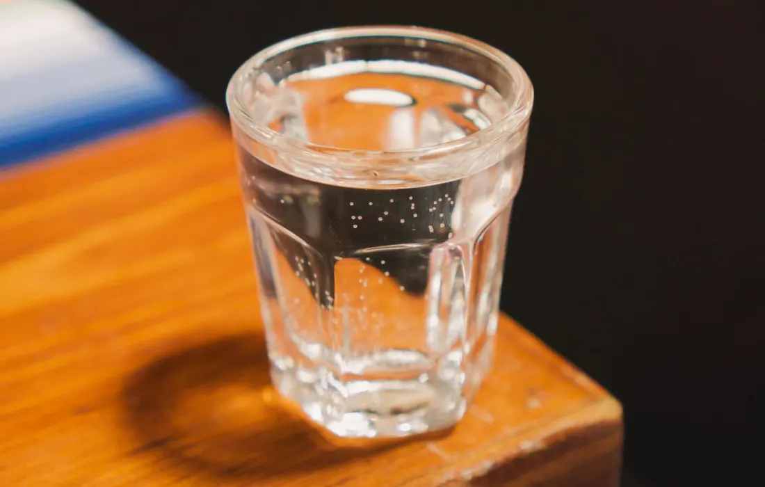 A glass of water on a wooden table.