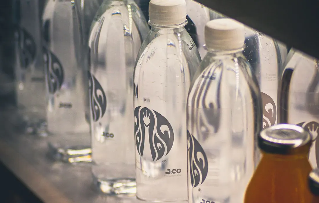 Bottled drinks arranged on a refrigerator shelf.