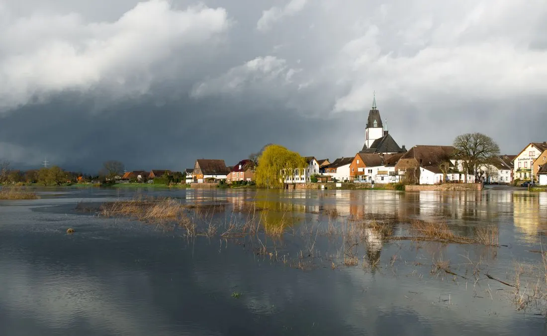 Peaceful river landscape with historic church and cloudy sky in Höxter, NRW, Germany.