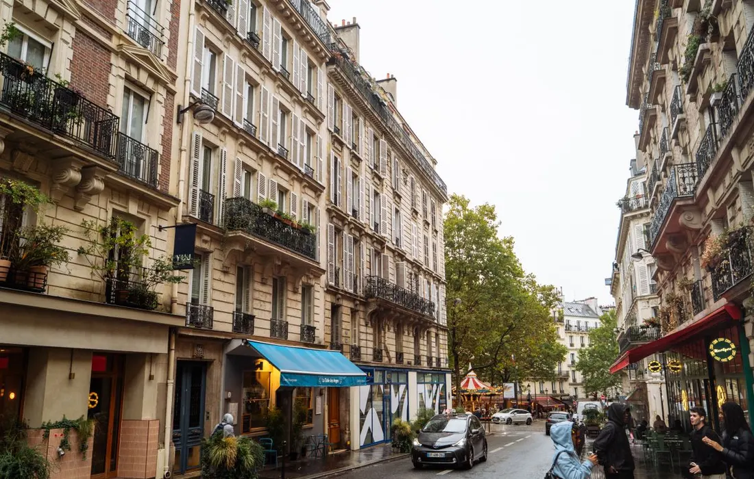 Classic Parisian buildings beside a wet street.
