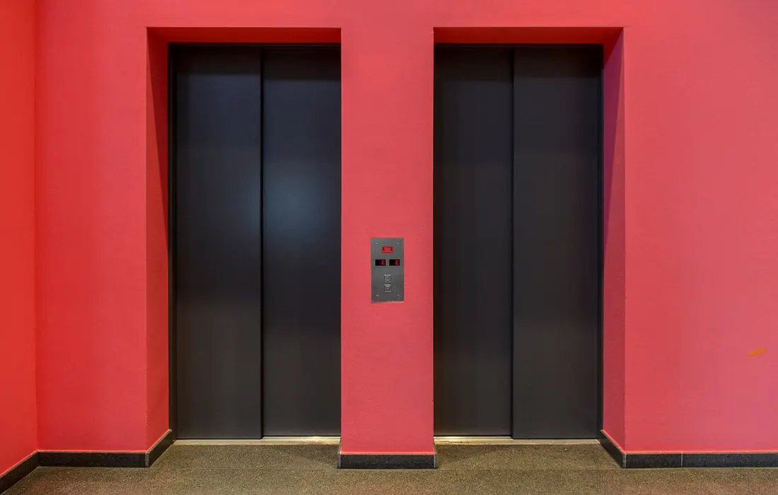 Closed lift doors set into a red interior wall.