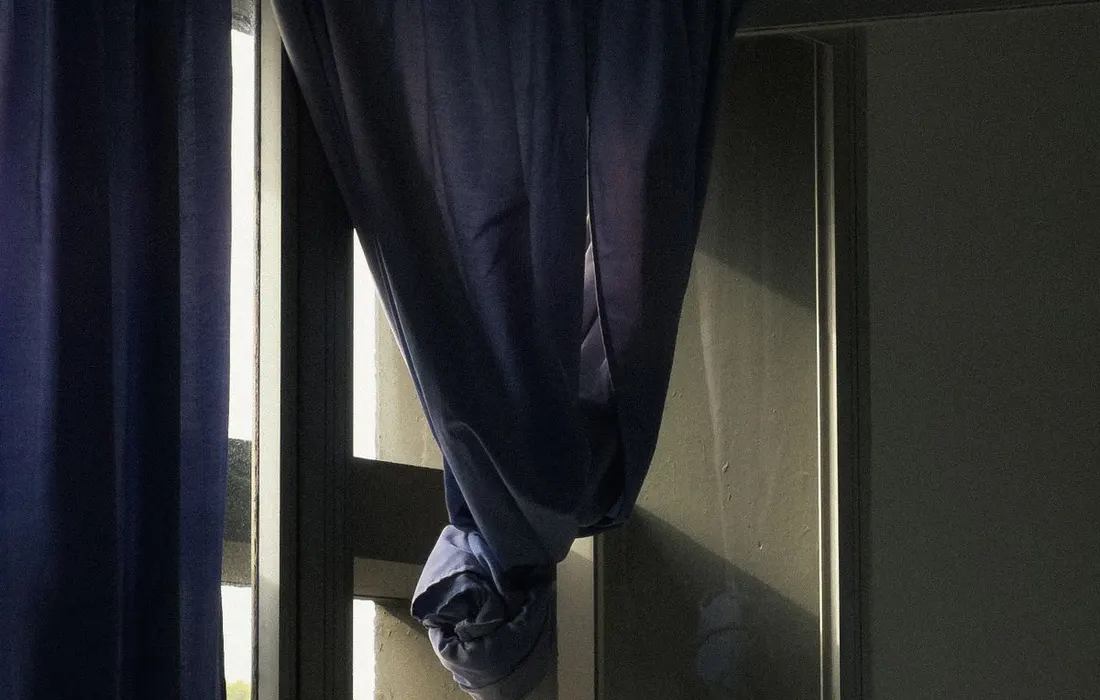 An open window and blue curtains in a sunlit room.