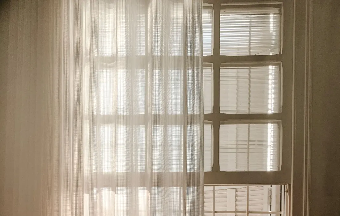 An open white window with sheer curtains.