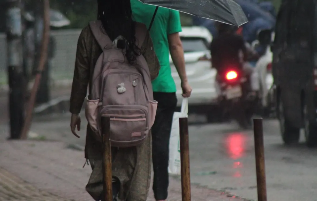 A person with an umbrella on a rain-soaked street.