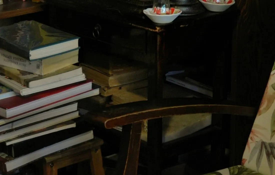 An armchair and stacks of books in a quiet reading space.