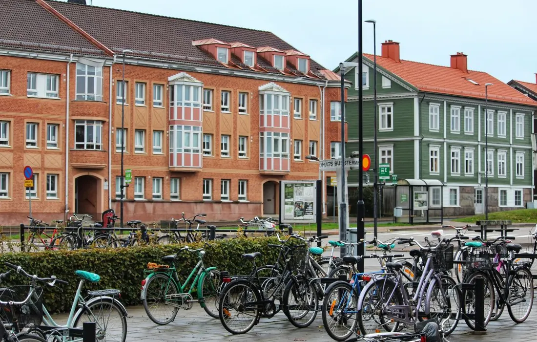 Bicycles parked along a Swedish street near a bus stop.