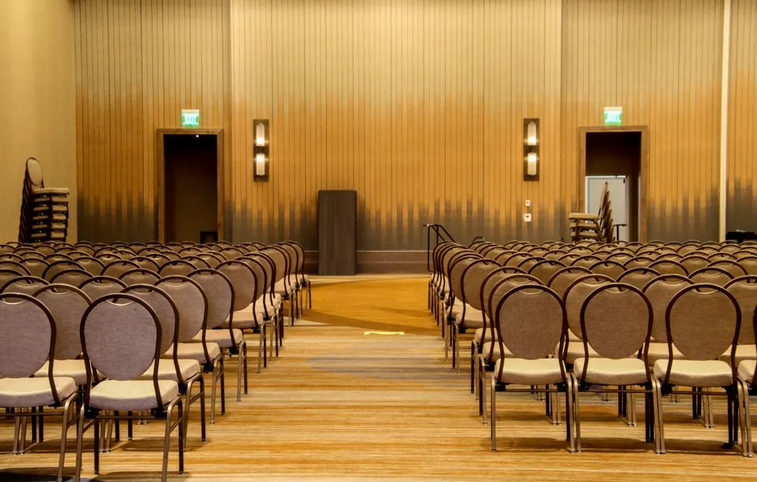 Rows of empty chairs arranged inside a large meeting room.