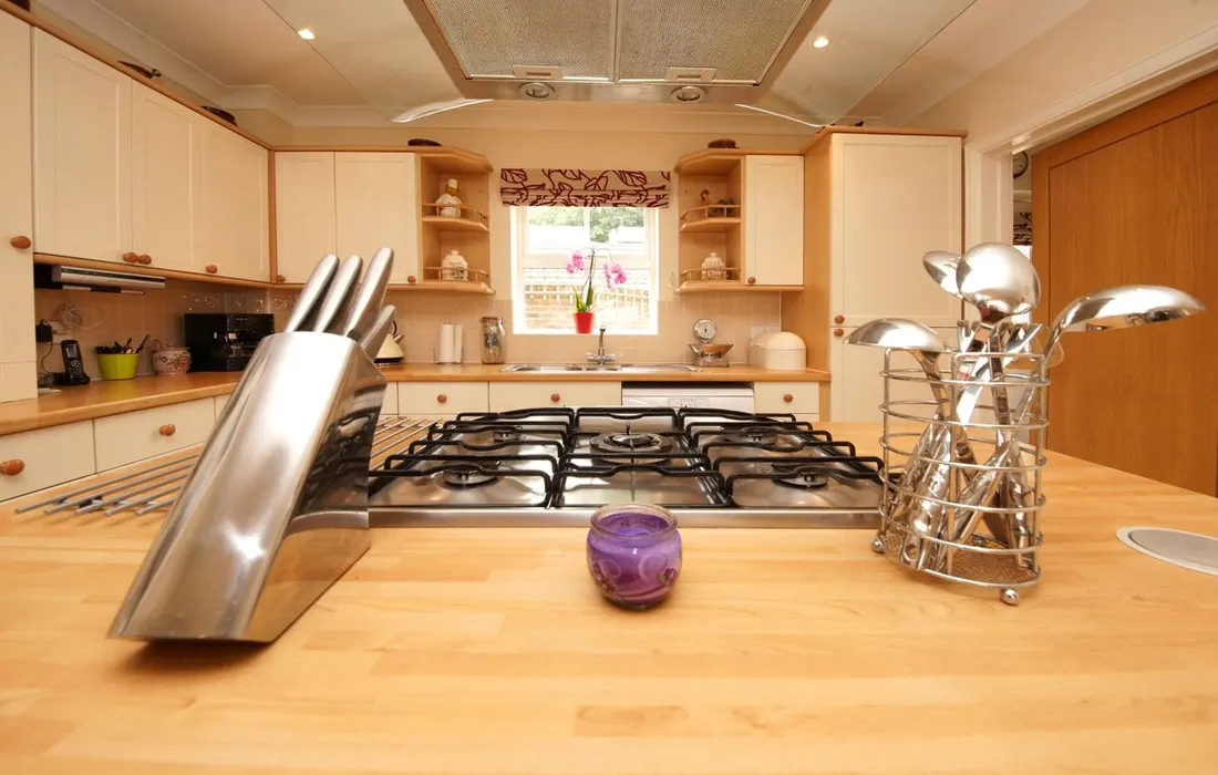 An unoccupied kitchen with a gas hob and a wooden counter.