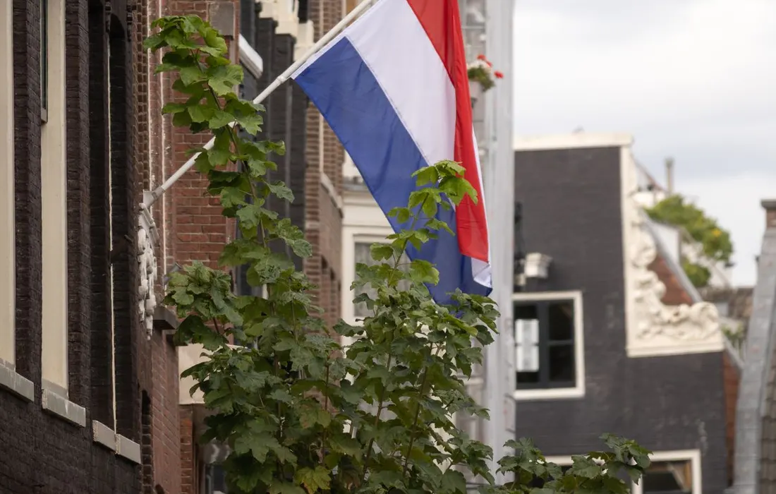 A Dutch flag hanging above an Amsterdam street.