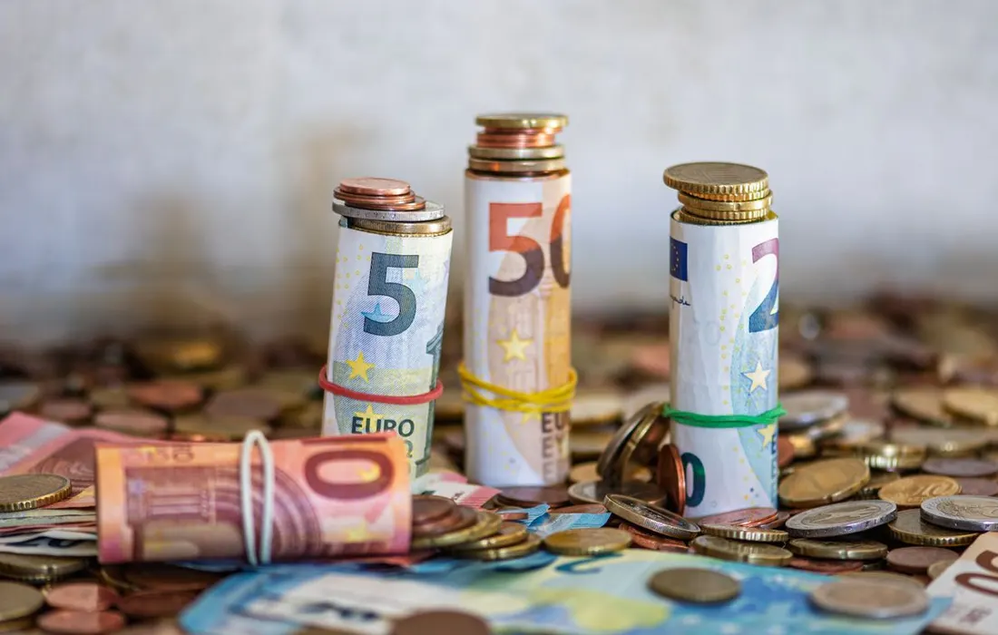 Euro banknotes and coins arranged on a table.