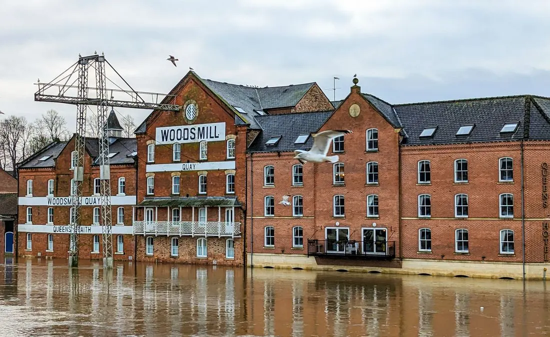 Flooding at Woodsmill Quay, York, with visible high water levels and seagulls flying.