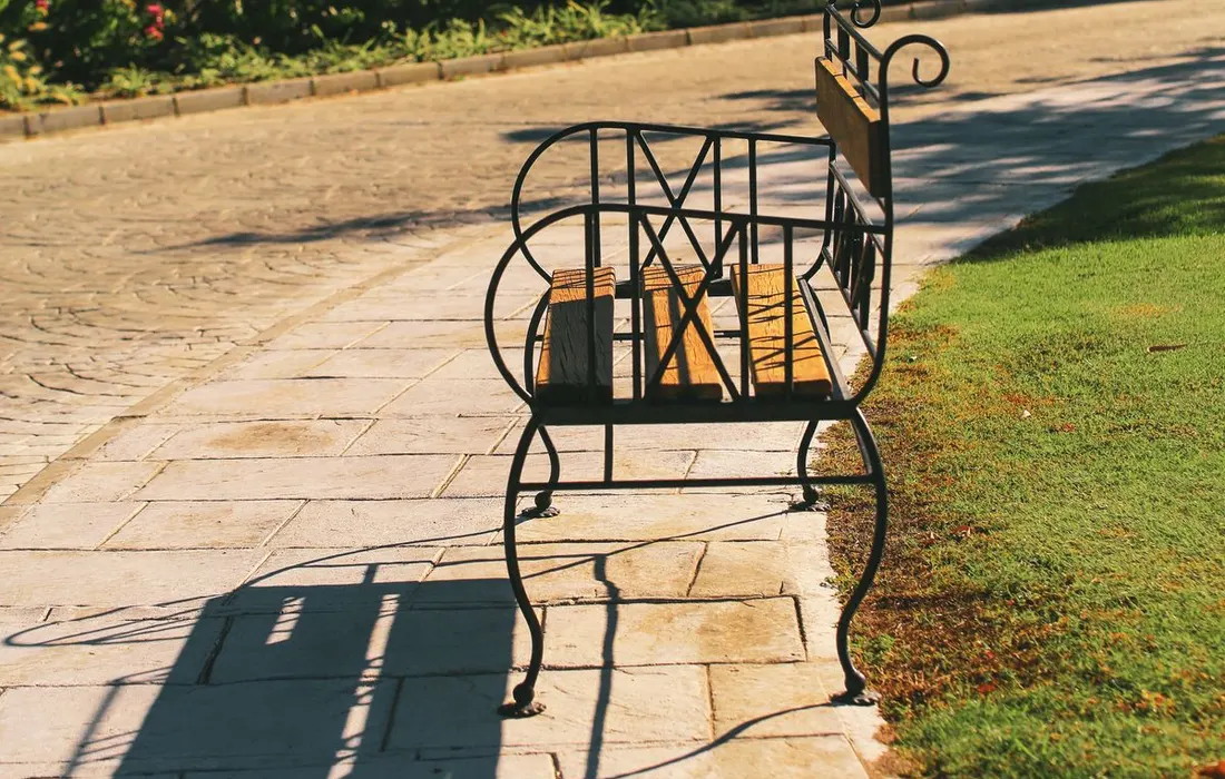 A park bench beside a sunlit path.