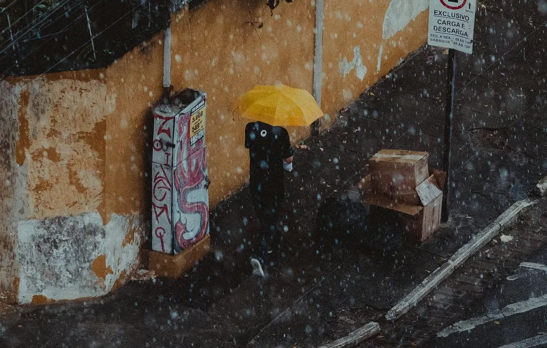 A person under a yellow umbrella on a rainy city street.