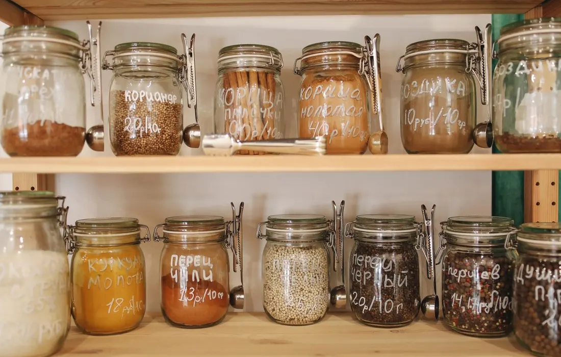 Food jars arranged on wooden pantry shelves.