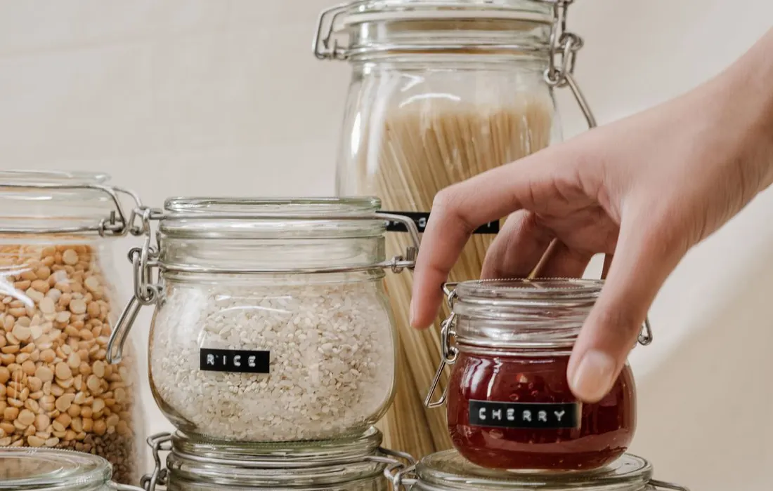 A hand holding a labelled food-storage jar.