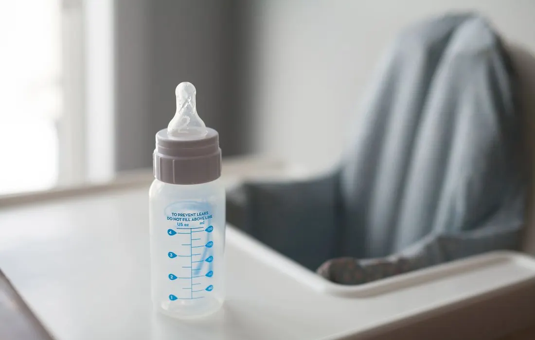 A baby bottle standing on a high-chair tray.