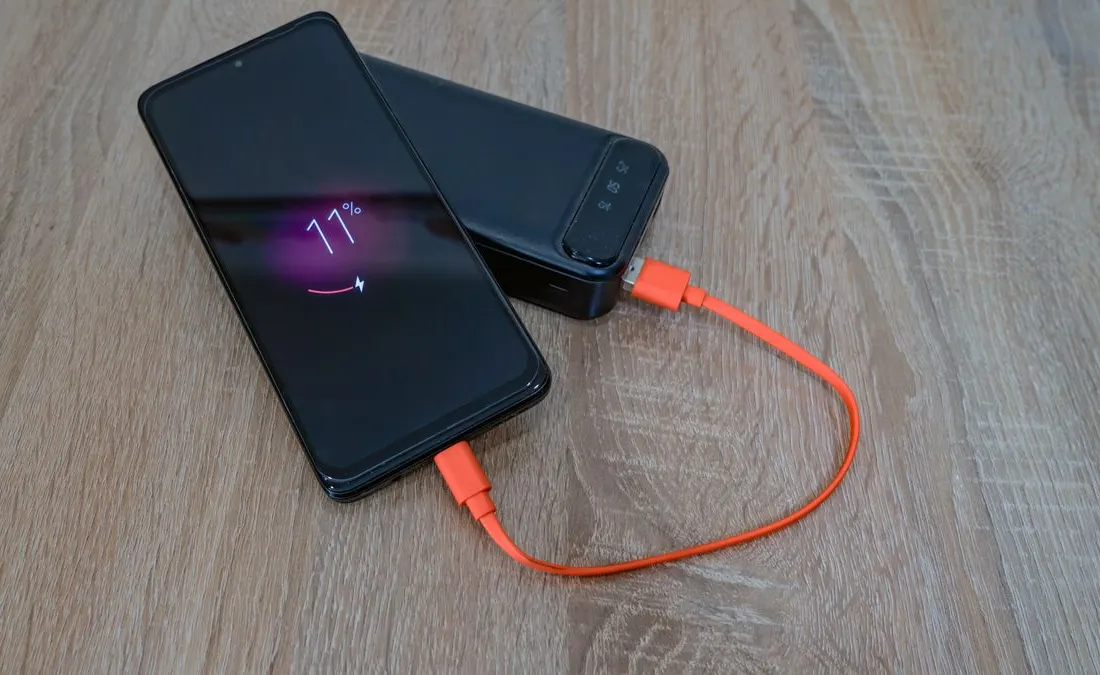 A smartphone connected to a portable power bank.