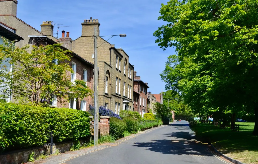 A residential street with houses and green verges in an English suburb.