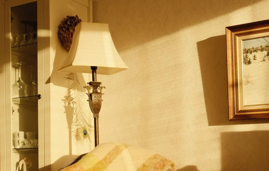Warmly lit cozy corner with a chair, blanket, and lamp. Perfect for relaxation.