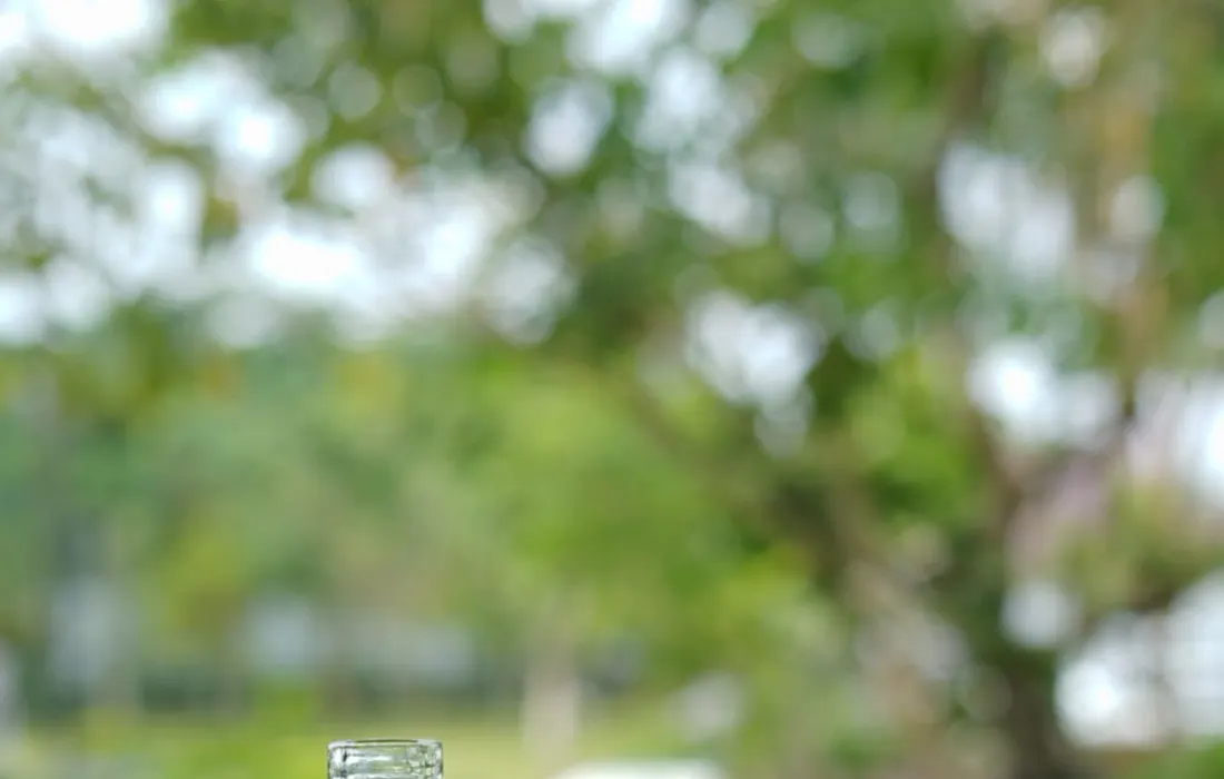 A bottle and glass of water on an outdoor table.