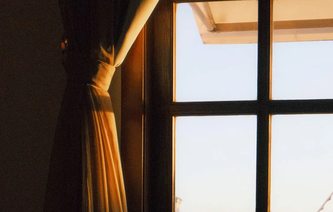 Warm sunlight filtering through window curtains.