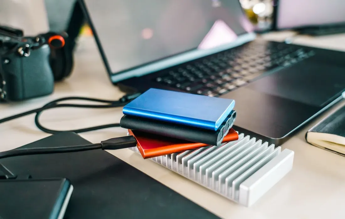 External storage drives and a laptop on a work desk.